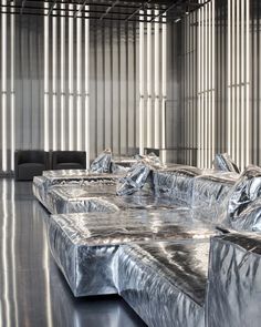 an artisticly designed metal couch in a large room with vertical blinds on the wall