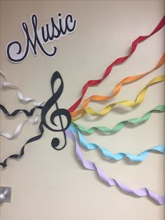 colorful streamers with music written on them in front of a white wall that says music