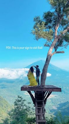 two people standing on top of a wooden platform next to a tree with the words pov this is your sign to visit bali