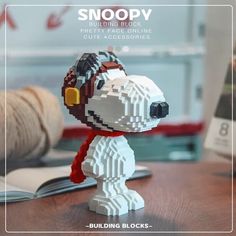 a lego dog with headphones on top of a wooden table next to a book