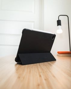 an ipad case sitting on top of a wooden table next to a lamp and phone