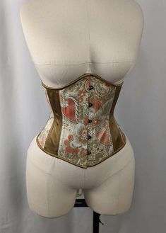 Ivory Gold and Coral Brocade and Satin Steel Boned Low Curve Mid Hip Underbust Corset This listing is for a made to order corset made using our custom pattern! This corset is perfect for victorians and goths alike.  This corset is made of an Ivory Gold and Coral Brocade, tied together with Gold satin inserts and binding, Ivory laces, antique brass colored hardware, and a floating boned lacing panel.   Our 225 Pattern is a low curve underbust that is perfect for newer corset wearers as well as cu Elegant Underbust Corset With Satin Finish, Underbust Satin Corset With Satin Finish, Elegant Silk Overbust Corset, Fitted Silk Overbust Corset, Gold Underbust Corset, Waist Corset, Underbust Corset, Gold Satin, Lace Panelled