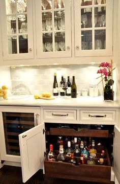 an open cabinet in a kitchen filled with bottles and glasses