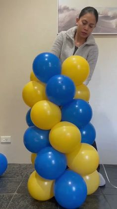 a woman standing next to a bunch of blue and yellow balloons