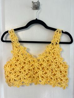 a yellow crochet bra hanging on a white door