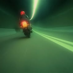 a person riding a motorcycle in the middle of a tunnel with green light coming from behind