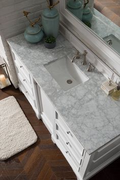 a bathroom vanity with marble counter top and white cabinets, along with a rug on the floor