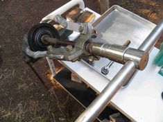 a machine that is sitting on top of a table in the woods with tools around it