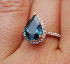 a woman's hand holding a blue and white ring with diamonds on the band