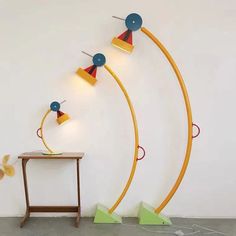 three yellow and blue lamps sitting on top of a table next to a white wall