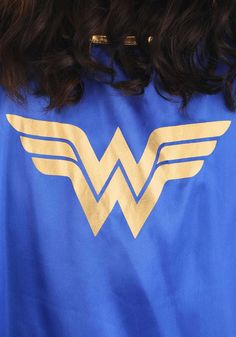 the back of a woman's blue shirt with gold wonder women logo on it