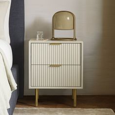 a nightstand with a mirror on it next to a bed