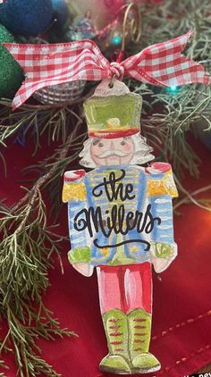 a christmas ornament hanging from a tree with ornaments around it and the words the millers on it