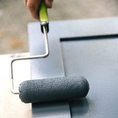 a person using a roller to paint a metal surface