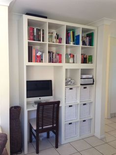 a computer desk sitting in front of a white book shelf