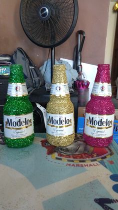 three bottles of modelo are sitting on a table next to a fan and other items