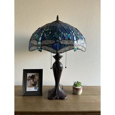 a table lamp sitting on top of a wooden table next to a potted plant