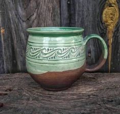 a green and brown mug sitting on top of a wooden table