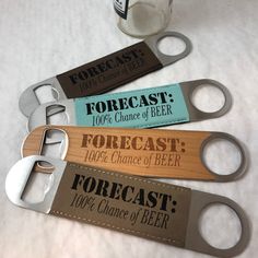 four bottle openers with labels on them sitting next to a glass of beer and a corkscrew