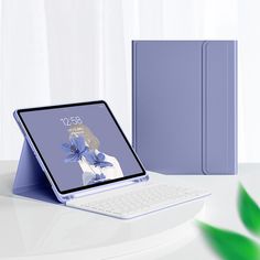 an open laptop computer sitting on top of a white table next to a blue book