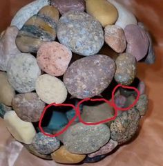 there is a ball made out of rocks with a red heart on it's side