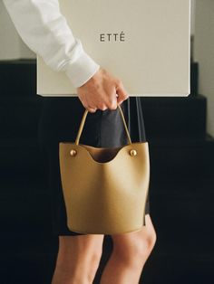 ETTE seeks to achieve a harmony between the sentiment of retro and modern design. We hope that our products, crafted with classic materials and artisanal spirit, will accompany you for a long time. - Compact-sized bucket bag style- Made of textured and glossy leather- Single leather top handle- Snap strap closure at the opening- Natural and flexible body shape On-the-go Bucket Bag With Adjustable Strap, Minimalist On-the-go Bucket Tote Bag, On-the-go Bucket Bag Tote With Adjustable Handle, Bucket Bag Style, Flexible Body, On-the-go Double Handle Bucket Bag With Zipper Pocket, W Concept, Bag Style, Leather Top