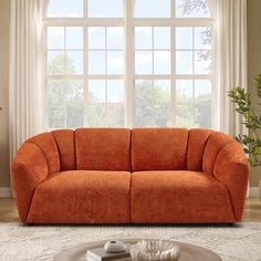 an orange couch sitting in front of a window