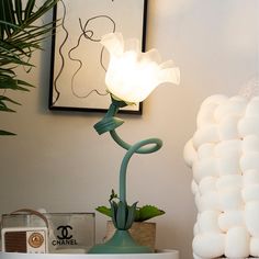 a white flower sitting on top of a green vase next to a mirror and lamp