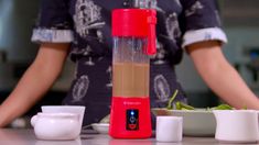 a blender sitting on top of a counter next to cups