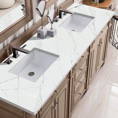 two white sinks sitting under a large mirror in a bathroom next to a counter top