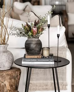 two vases with flowers and candles sit on a table in front of a couch