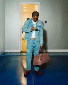 a man standing in a room with a bag and cell phone