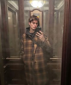 a young man taking a selfie in front of a mirror with his cell phone