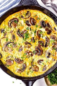 an omelet with mushrooms and parsley in a cast iron skillet on a table