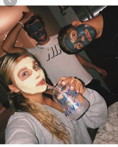 two men and a woman with facial masks on drinking from a water bottle while standing next to each other