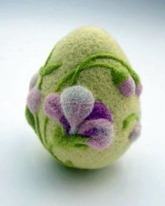 a small green and pink ball with flowers on it sitting on a white table top