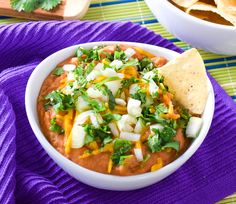 a white bowl filled with guacamole and tortilla chips on top of a purple towel