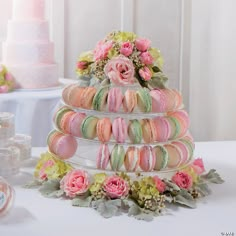 a stack of macaroons sitting on top of a table next to pink flowers