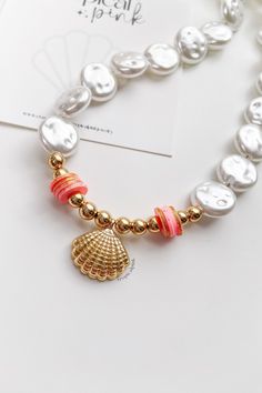 🐚 our 𝓝𝓪𝓾𝓽𝓲𝓬𝓪𝓵 𝓒𝓸𝓵𝓵𝓮𝓬𝓽𝓲𝓸𝓷 is here! 🐚🤍✨🥥 This beautiful golden clam choker will add a touch of elegance to your summer outfit! 😎

MATERIALS
⭐ faux pearl beads
⭐ gold plated beads
⭐ glitter polymer clay beads
⭐ 18k gold plated clam pendant

DETAILS
Closure: Lobster clasp
Size: 17.5 Inches

CARING TIPS
🤍 Keep your jewelry dry and away from perfumes or any harsh chemicals
🤍 Store your jewelry separately, and avoid wearing it if you are going to work out.

If you have any questions, please feel free to message me.
Thank you so much for visiting my shop!
Have fun creating your favorite combinations and enjoy your new jewelry! ♥♥♥ Gold Beaded Shell Bracelets, Adjustable Gold Beaded Shell Necklace, Beach Pearl Jewelry With Gold Beads, Pearl Jewelry With Gold Beads For Beach, Gold Choker With Round Beads For The Beach, Beach Pearl Necklace With Colorful Beads In Gold, Gold Beaded Shell-shaped Jewelry, Gold Pearl Necklace With Colorful Beads For Beach, Gold Choker With Colorful Beads For Beach