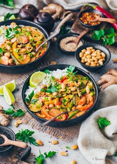 two black bowls filled with rice, vegetables and chickpeas on top of a table