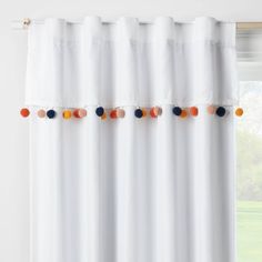 white curtains with multi colored pom - poms hanging on the top and bottom