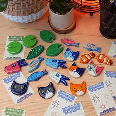 there are many magnets on the table with different colors and shapes, including cats