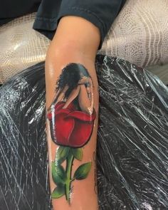 a woman's arm with a tattoo on it that has a red rose in the center