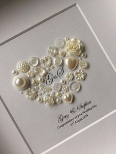 a wedding card with buttons and flowers in the shape of a heart, on a white background