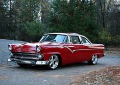 an old red car is parked on the road