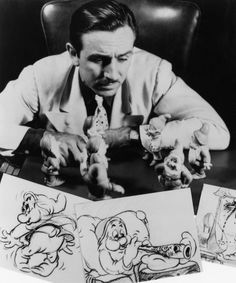 a man sitting at a desk with some drawings on it