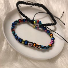 two beaded bracelets sitting on top of a white plate with a black cord