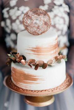 a white and gold wedding cake with an ornament on top