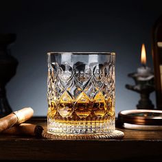 an old fashioned whiskey glass with two skulls on it and some cigars next to it