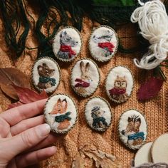 someone is holding their hand out to some small embroidered animal magnets on a sweater